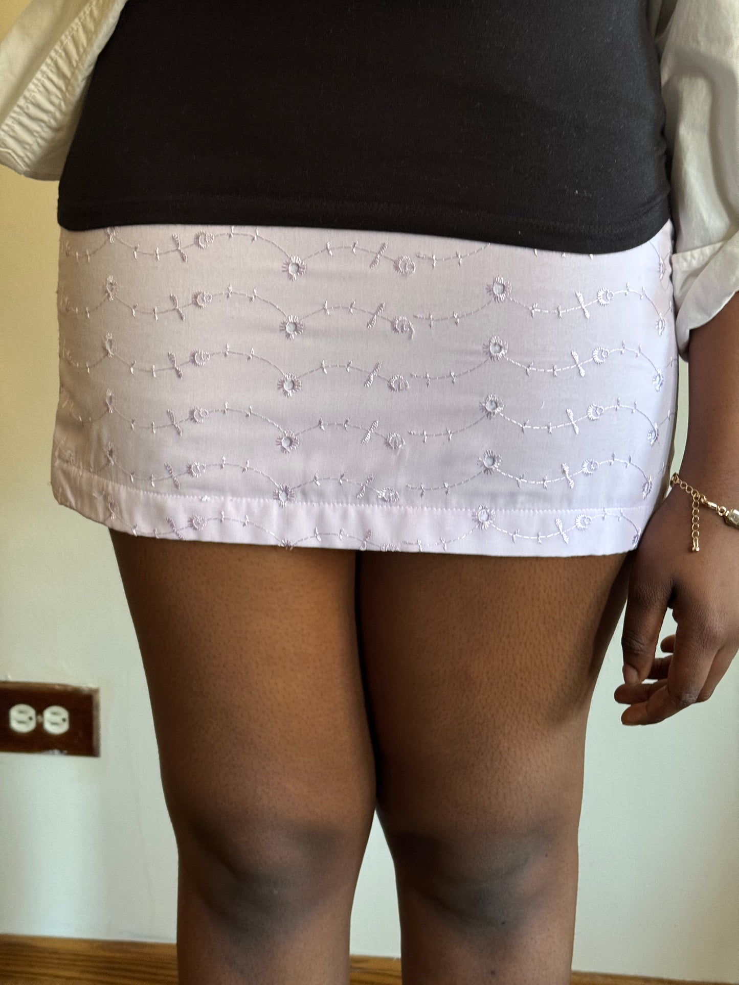 Romantic purple mini skirt with sculpted waist and floral detail, styled for brunch or gallery visits.